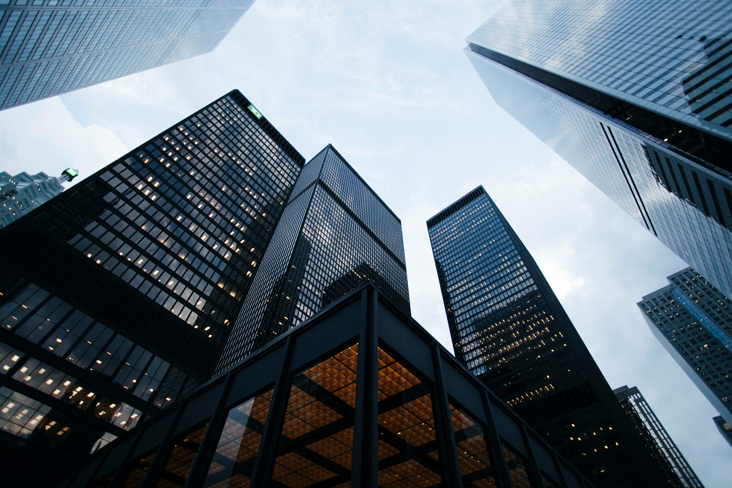 Modern office skyscrapers viewed from street level against a cloudy sky.