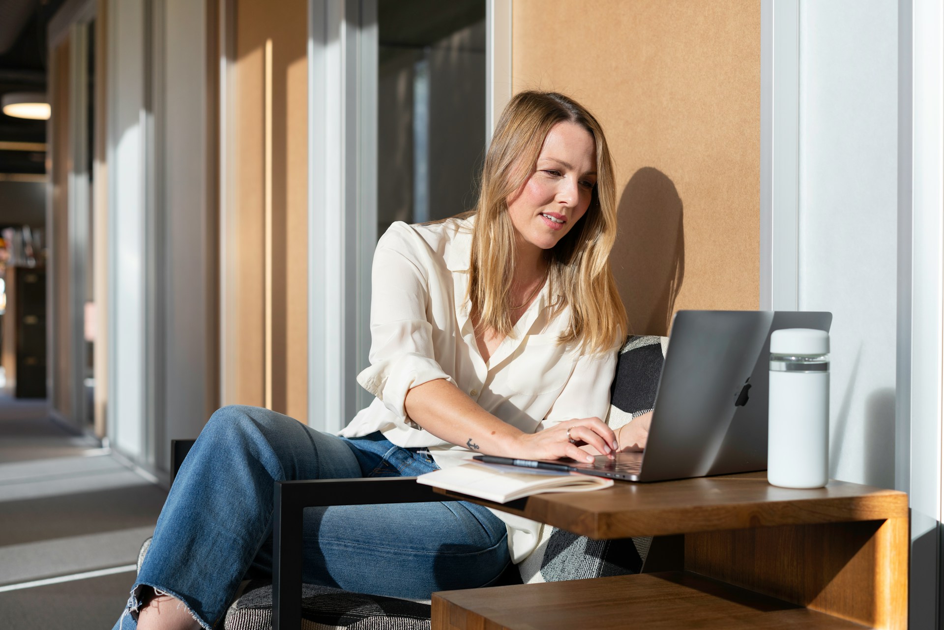 Woman working on a laptop in a sunlit office.