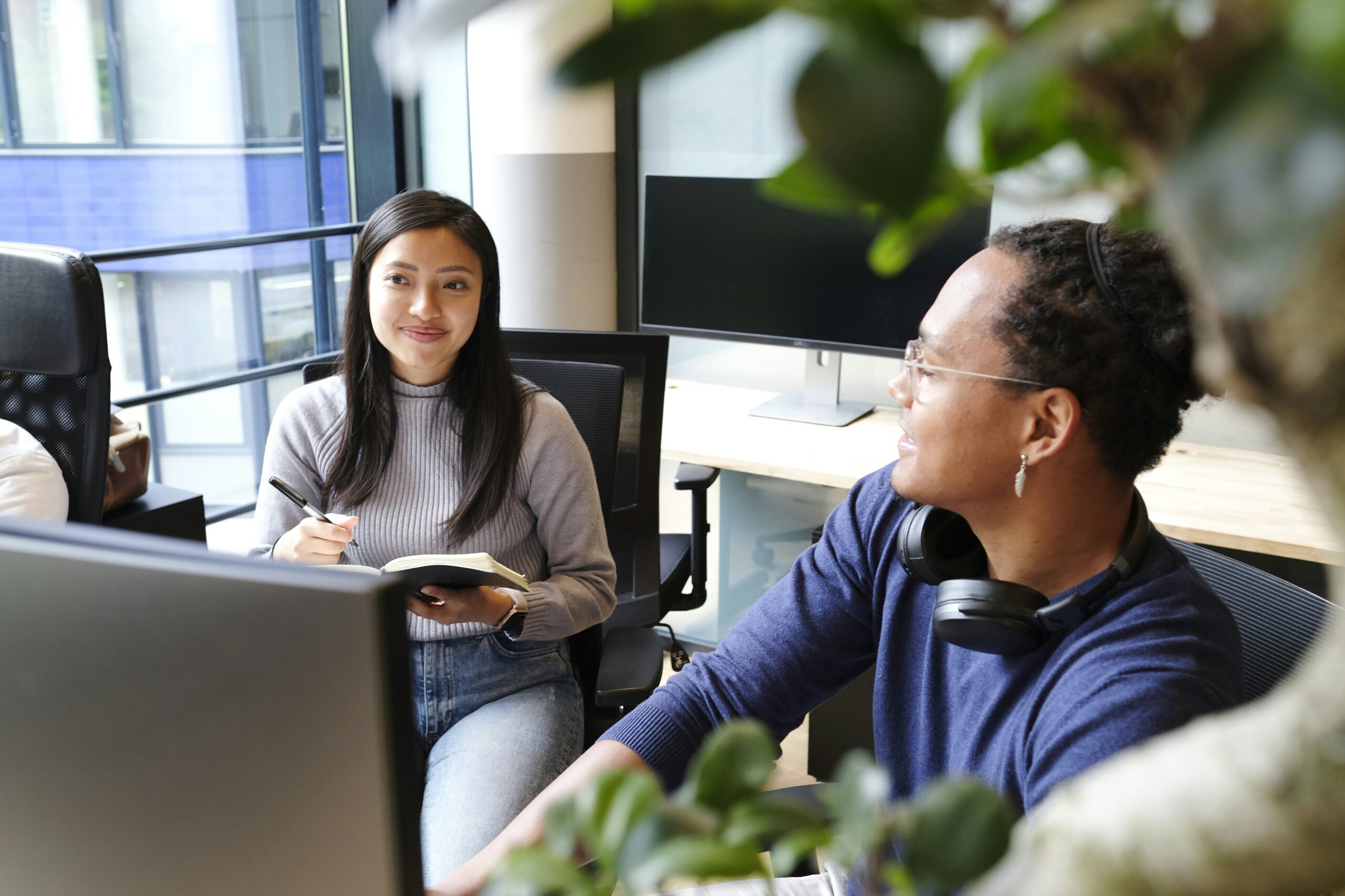 Two coworkers collaborating during a discussion in a modern office workspace.